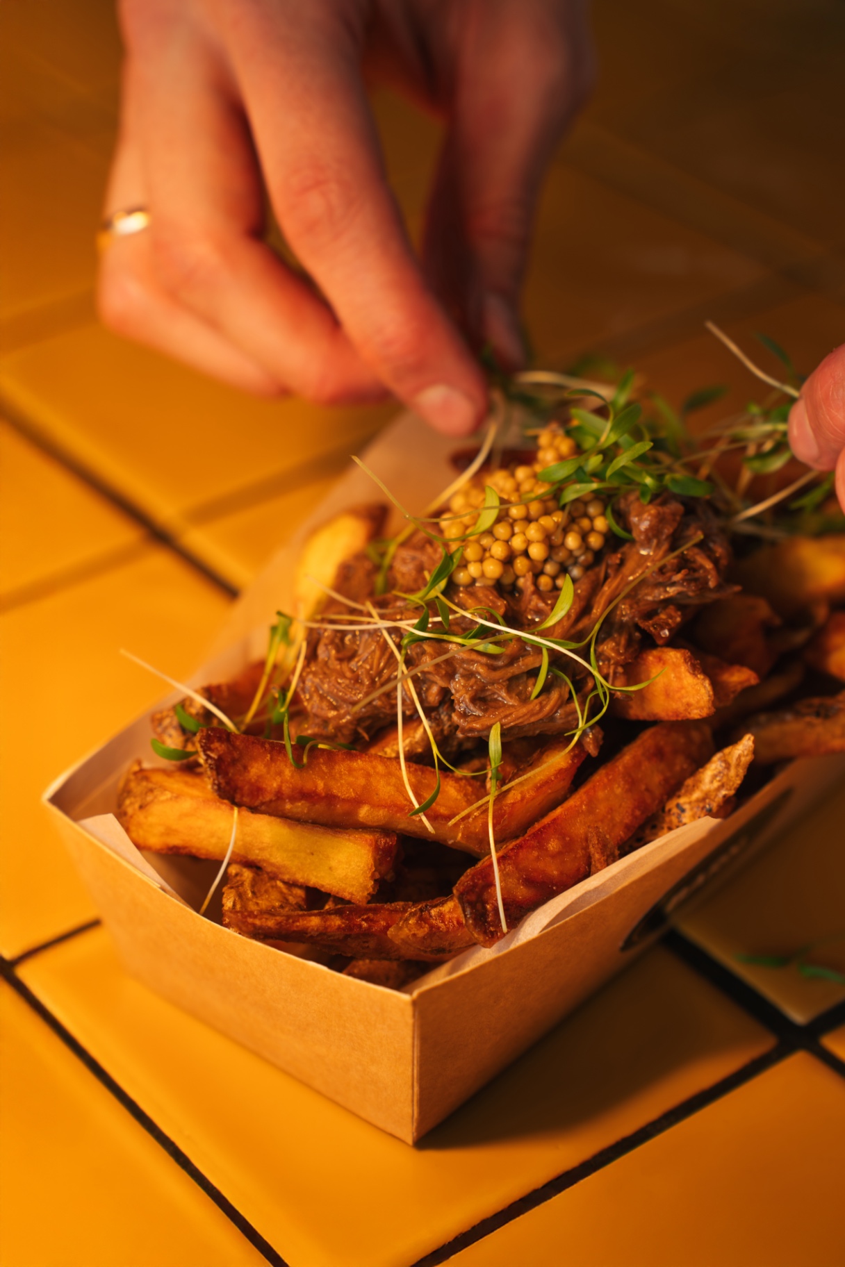 Loaded fries topped by hand